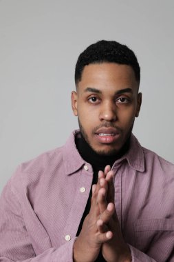 Milenyum Afrikalı Amerikalı adam beyaz duvarın üzerinde poz veriyor ve günlük gömlekler giyiyor.