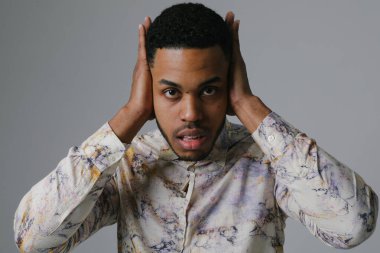 Genç siyahi adam stres ve baş ağrısı, kulaklarını duygusal ifadeyle kapatıyor.