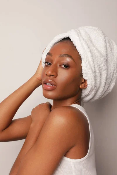 Jovem negra afro mulher vestindo toalha branca sentada junto à parede. Foto vertical. — Fotografia de Stock