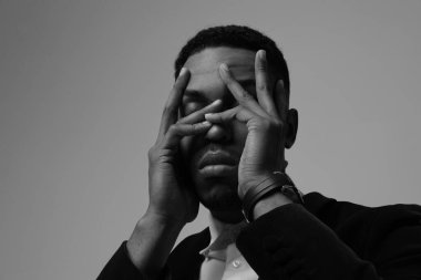 Yüzüne dokunan Afro-Amerikan adamın siyah-beyaz portresi. Zihinsel sorunlar