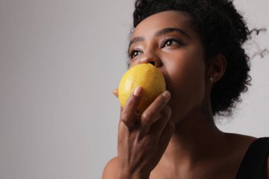 C vitamini konsepti. Meyveli limonlu koyu tenli kadın. Meyvelerden gelen enerji.