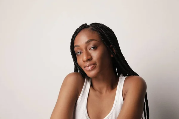 Photo of happy young woman with shining skin and long braids posing over white. — Stock Photo, Image