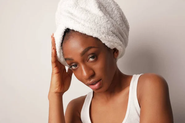 Jovem negra afro mulher vestindo toalha branca sentada junto à parede. Rotina matinal. — Fotografia de Stock