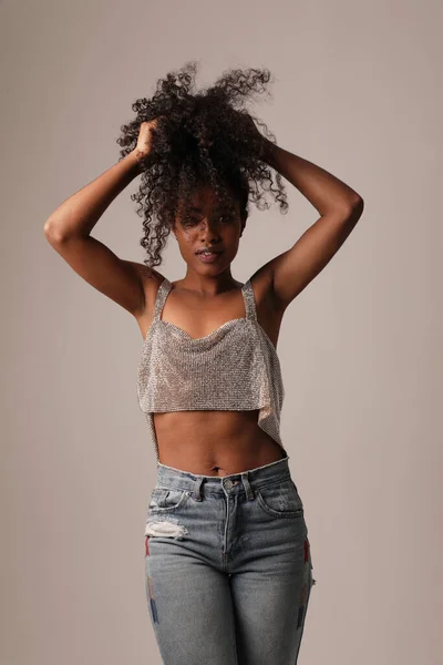 Portrait of beautiful young black woman posing and dancing on grey wall. — Stock Photo, Image