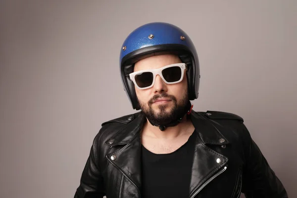 Hombre motorista barbudo posando en chaqueta de cuero y casco de moto azul. — Foto de Stock