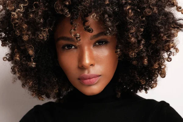 Afro-Amerikan güzeli. Beyaz arka planda kıvırcık saçlı genç bir kadın..