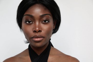 Beyaz duvarın üzerinde poz veren sağlıklı ciltli genç bir kadının kesilmiş portresi..