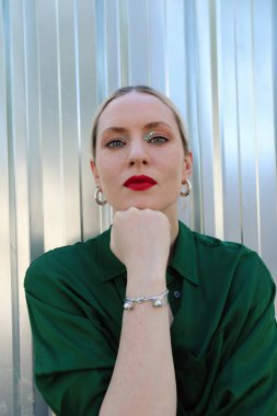 Açık havada poz veren kendine güvenen genç bir kadının fotoğrafı. Dikey.