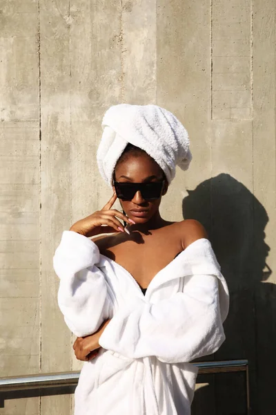 Femme afro élégant enveloppé dans une serviette blanche posant sur fond gris. — Photo