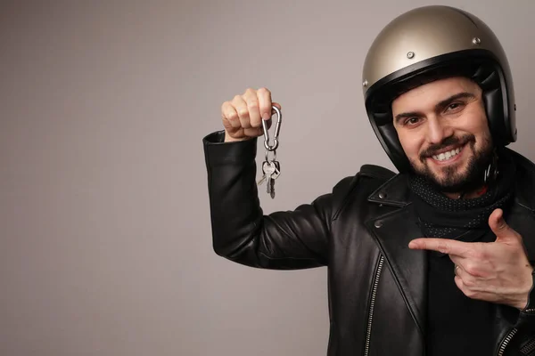 Feliz motorista hombres sostiene las llaves de la motocicleta con chaqueta de cuero y casco retro. — Foto de Stock