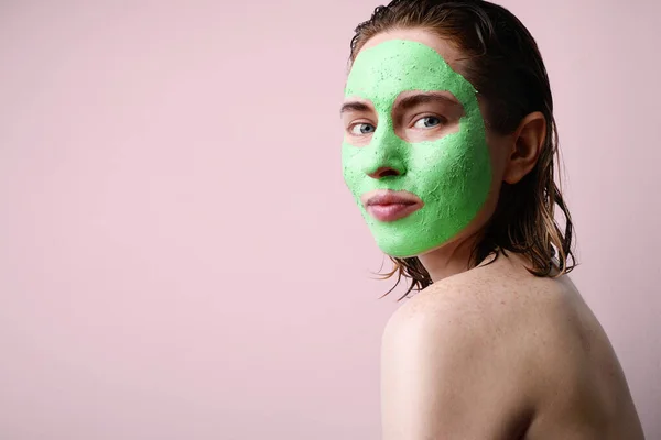 Šťastná žena s hydratační avokádově zelenou obličejovou maskou. Krása a péče o pleť. — Stock fotografie