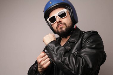 Deri ceketli ve motosiklet kasklı sakallı motorcunun kesilmiş portresi..