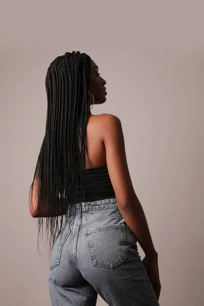 Beyaz duvarda poz veren uzun örgülü Afro Amerikalı genç bir kadının arka görüntüsü.. — Stok fotoğraf
