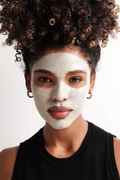 Yüzünde nemlendirici maske olan genç bir kadın kameraya bakıyor. Dikey. — Stok fotoğraf