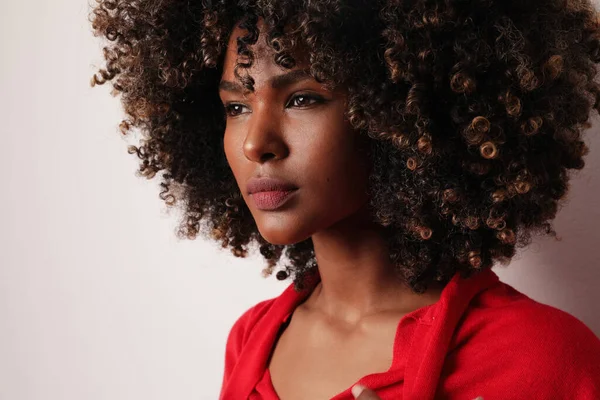 Close-up de atraente jovem mulher no topo vermelho, com cabelo encaracolado na parede branca. — Fotografia de Stock