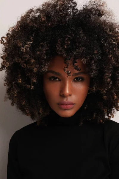 Portrait of Black American woman with curly brown hair looking at the camera.