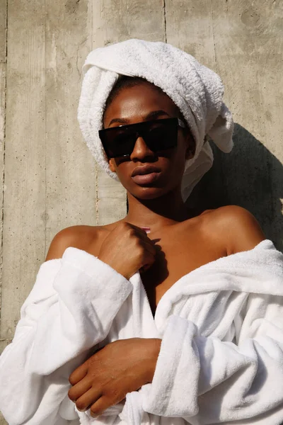 Retrato vertical de jovem envolto em toalha branca posando sobre a parede cinza. — Fotografia de Stock