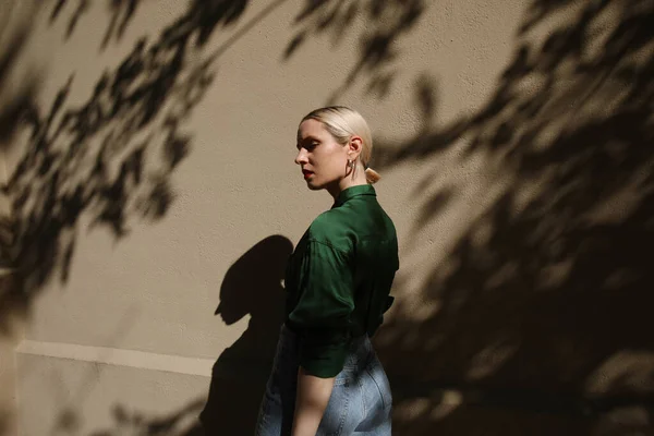 Porträt einer jungen blonden Frau posiert auf beiger Wand mit dunklen Schatten. — Stockfoto