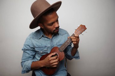 Beyaz arka planda ukulele çalan genç yakışıklı adamın vesikalığı..