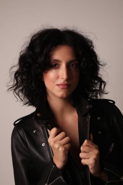 Gülümseyen genç bir kadının portresi beyaz arka planda poz verirken yüzüne dokunur.