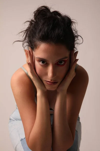 Mujer joven y bonita toca su cara posando sobre fondo blanco. Aislado. —  Fotos de Stock