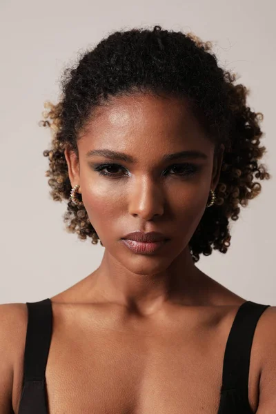 Beautiful African American young woman with curly black hair posing on white. — Stock Photo, Image