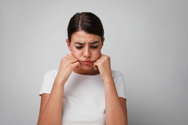 Stüdyoda beyaz duvara poz veren üzgün yüzlü bir kadın. İzole edilmiş.