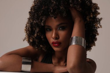 Beyaz arka planda poz veren kıvırcık saçlı güzel bir genç kadın. İzole edilmiş.