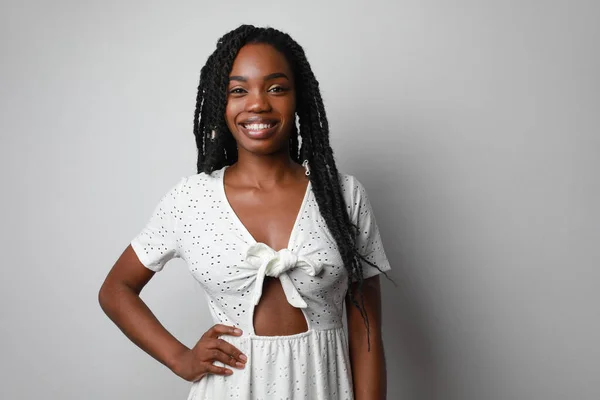 Χαμογελώντας ελκυστική νεαρή Αφρικανή με πλεξούδες που ποζάρουν πάνω από λευκό τοίχο. — Φωτογραφία Αρχείου