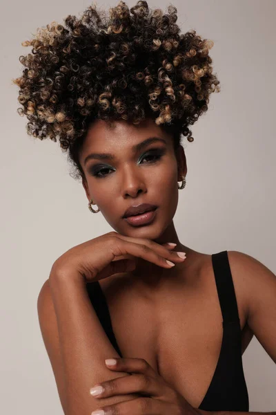 Beyaz poz veren kıvırcık siyah saçlı güzel etnik bir genç kadın. Dikey. 