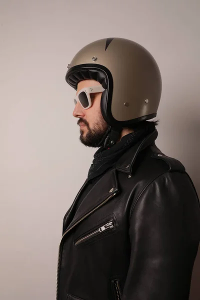 Vertikales Porträt eines Motorradfahrers, der in Lederjacke und Motorradhelm posiert. — Stockfoto