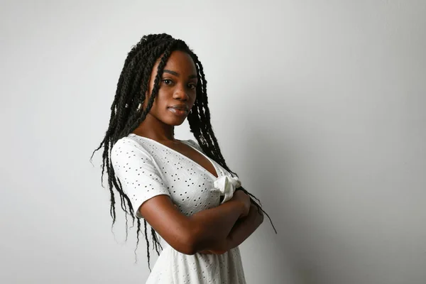 白い壁の上にポーズをとって長い毛を持つ若いアフリカ人女性のプロフィール写真. — ストック写真