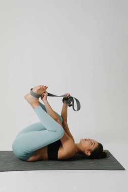 Beyaz arka planda yoga yapan sportif bir kadın. Dikey.