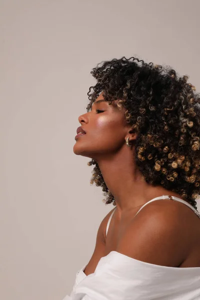 Side portrait of joyful woman with afro hair smiling over white background. — Stock Photo, Image