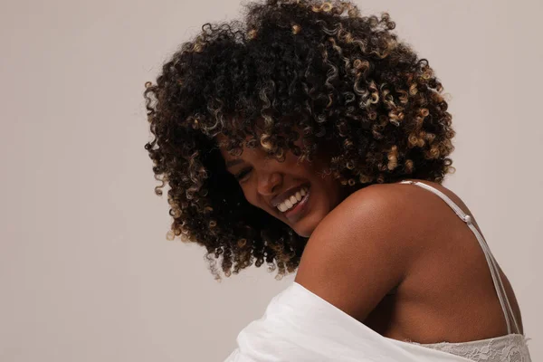 Side view of joyful woman with afro hair smiling over white background. — Stock Photo, Image