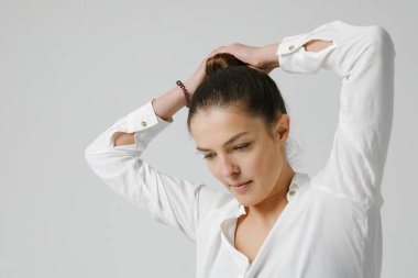 Keyifli bir kadın, rahat bir gömlek giyip, saçlarını tarıyor..