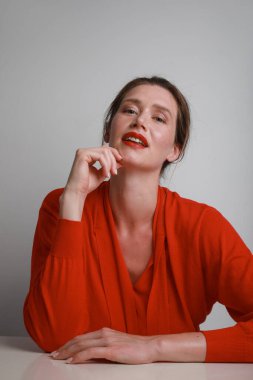 Kırmızılı genç kadın kameraya bakıyor, arka planda poz veriyor. Bitkisel.