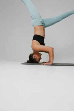 Beyaz arka planda yalnız başına yoga yapan genç bir kadın.. 
