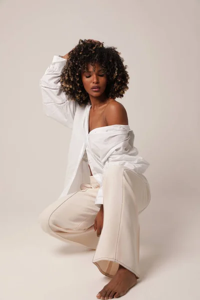Beyaz stüdyoda poz veren güzel siyahi bir kadının tam boy fotoğrafı.. 