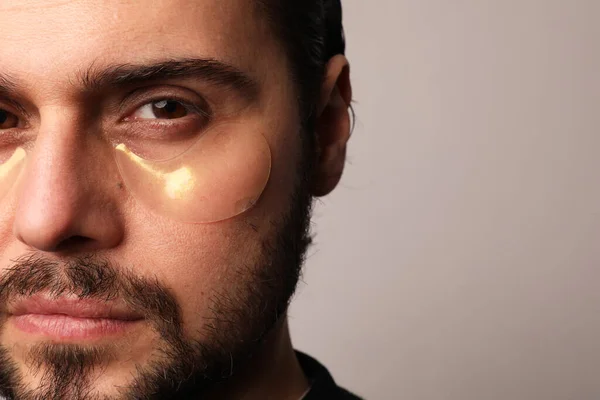 Potret close-up dari pria berjanggut mengenakan penutup mata yang terisolasi di dinding cahaya. — Stok Foto