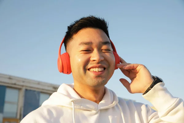 헤드폰으로 음악을 듣고 야외에서 포즈를 취하는 행복 한 젊은이의 모습. — 스톡 사진