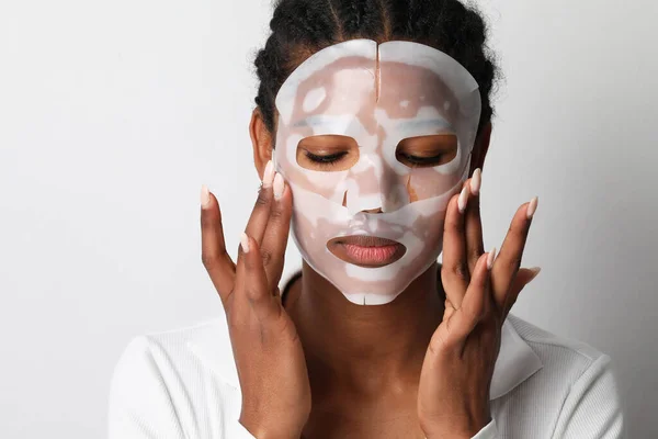 Чорна жінка наносить маску для обличчя з гідрогелю. Догляд за шкірою та косметичні процедури . — стокове фото