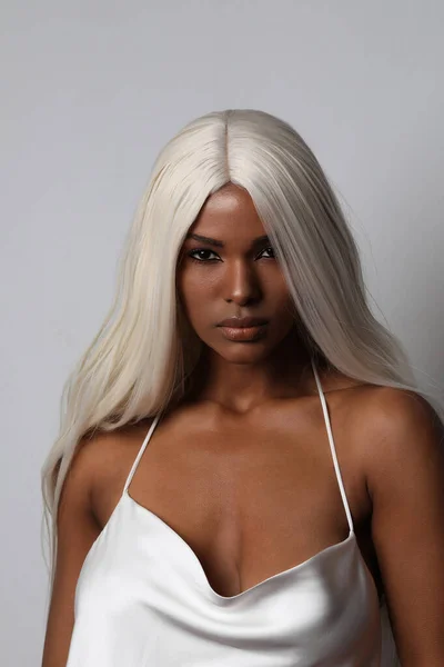 Egy vonzó fekete fiatal nő portréja, hosszú szőke hajjal. Függőleges. — Stock Fotó