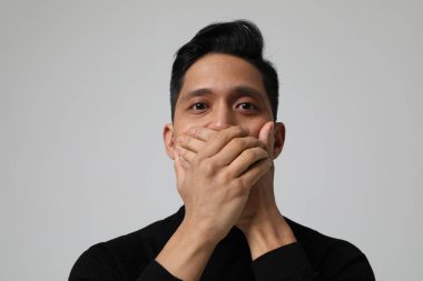 Asyalı adamın yakın plan portresi ağzını kapatıyor. Ruh sağlığı sorunları. 