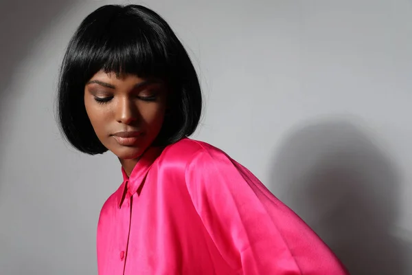 Pretty young woman with bob cut hair posing on the white wall. Isolated.