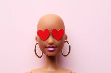 Aşk ve ilişki kavramı. Pembe duvarda iki kırmızı kalbi olan oyuncak bebek kafası..