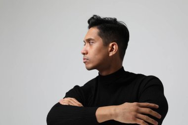 Ciddi bir Asyalı genç adam beyaz duvarın yanında poz veriyor. İş adamı kavramı. Model.