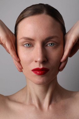 Stüdyoda taze parlak ciltli ve doğal makyajlı genç bir kadın. Dikey çekim.