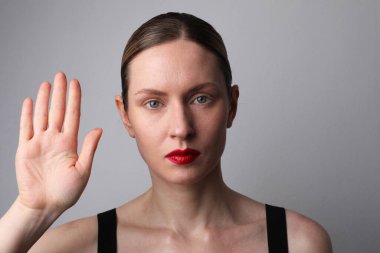 Taze parlak ciltli genç bir kadın elini kaldırıyor. Beyazda izole edilmiş.