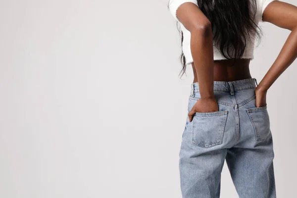 Vue arrière photo de la femme noire porter un jean bleu et haut isolé sur le mur gris. — Photo